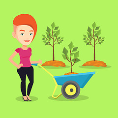 Image showing Woman pushing wheelbarrow with plant.