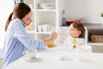 Image showing mother with smartphone feeding baby at home