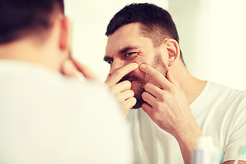 Image showing man squeezing pimple at bathroom mirror