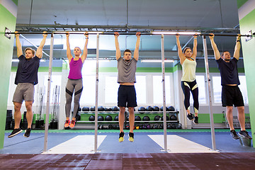 Image showing group of people hanging at horizontal bar in gym