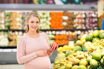 Image showing happy pregnant woman with pomegranate at grocery