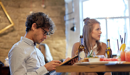 Image showing happy friends looking to menu at restaurant