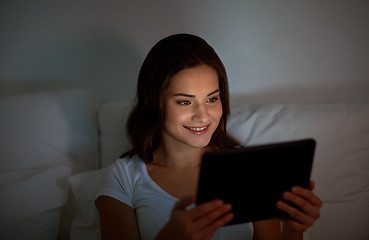 Image showing young woman with tablet pc in bed at home bedroom