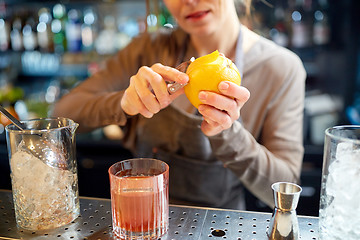 Image showing bartender peels orange peel for cocktail at bar