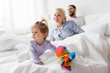 Image showing happy child with toys and parents in bed at home