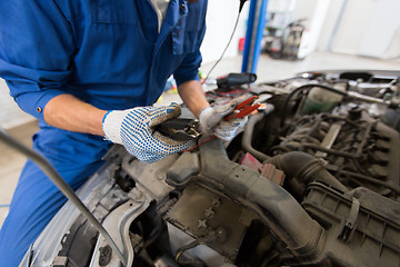 Image showing auto mechanic man with cleats charging battery
