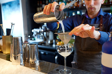 Image showing bartender with shaker preparing cocktail at bar