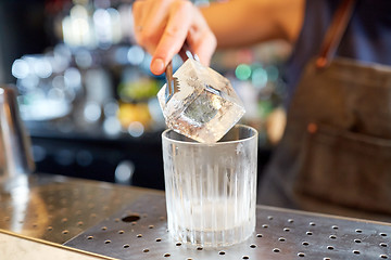 Image showing bartender adding ice cube into glass at bar