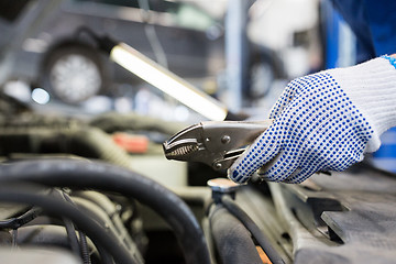 Image showing mechanic man with pliers repairing car at workshop