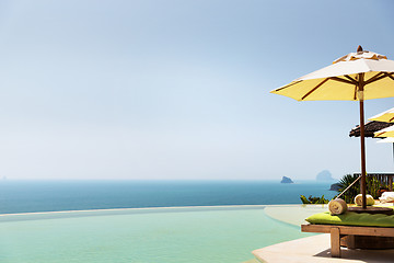 Image showing infinity pool with parasol and sun beds at ocean