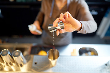 Image showing bartender with cocktail shaker and jigger at bar