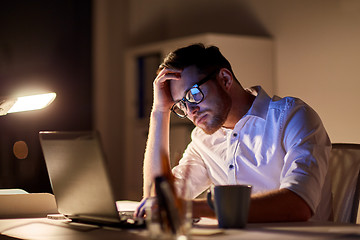 Image showing businessman with laptop thinking at night office