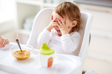 Image showing baby sitting in highchair and eating at home