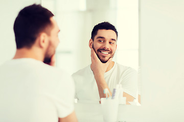 Image showing happy young man looking to mirror at home bathroom