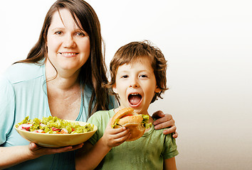 Image showing mature woman holding salad and little cute boy with hamburger te