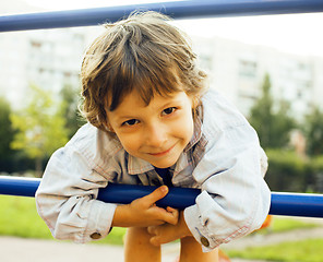 Image showing little cute boy playing on playground, hanging on gymnastic ring