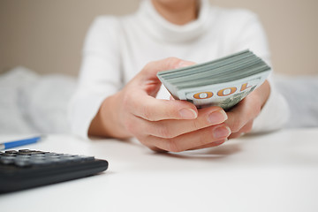 Image showing Close up of woman with calculator counting money