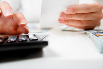 Image showing savings, finances, economy and home concept - close up of hands with calculator counting money and making notes at home