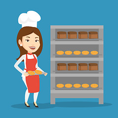 Image showing Happy young female baker holding tray of bread.