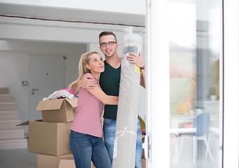 Image showing couple carrying a carpet moving in to new home