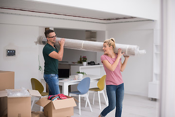 Image showing couple carrying a carpet moving in to new home