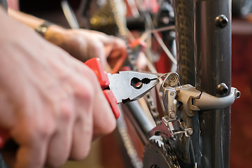 Image showing Man with pliers repairing bicycle