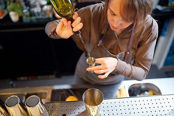 Image showing bartender pouring alcohol into jigger at bar