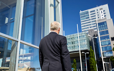 Image showing senior businessman walking along city street