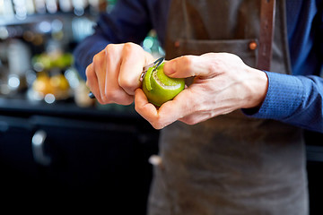 Image showing bartender removing peel from lime at bar