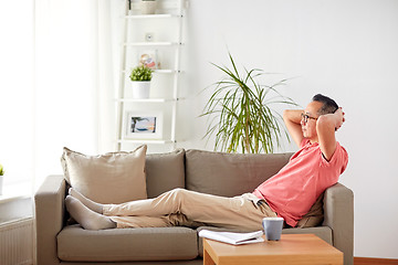 Image showing man in glasses relaxing on sofa at home