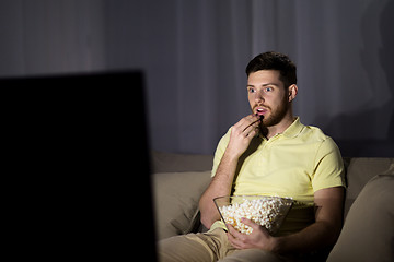 Image showing man watching tv and eating popcorn at night