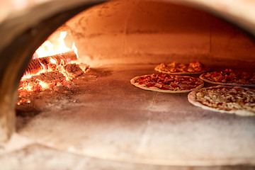 Image showing pizza baking in oven at pizzeria