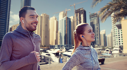 Image showing happy couple with earphones running in city