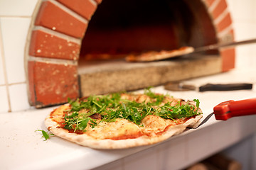 Image showing baked pizza on peel at pizzeria oven 