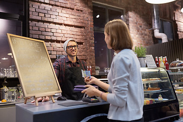 Image showing happy barman and woman paying money at cafe