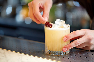 Image showing bartender with glass of cocktail and cherry at bar