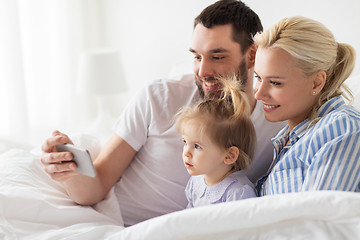 Image showing happy family with smartphone in bed at home