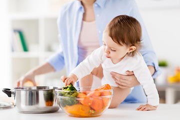 Image showing happy mother and baby cooking vegetables at home