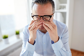 Image showing businessman in glasses rubbing eyes at office