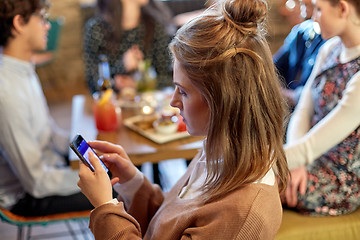 Image showing woman with smartphone and friends at restaurant