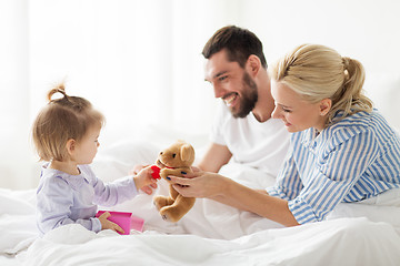 Image showing happy family with gift box in bed at home