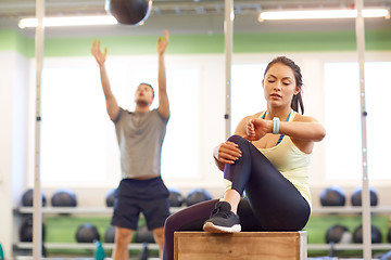 Image showing man and woman with ball and fitness tracker in gym