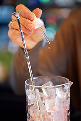 Image showing bartender adding essence to cocktail glass at bar