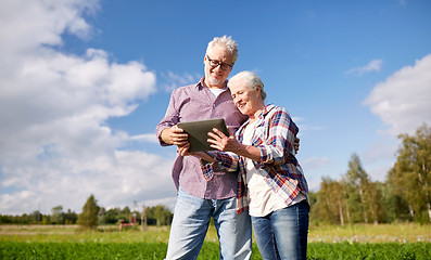 Image showing happy senior couple with tablet pc at summer farm