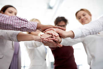 Image showing happy business team with hands on top at office