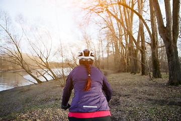 Image showing Brunette in helmet rides bicycle