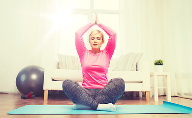 Image showing happy woman stretching leg on mat at home