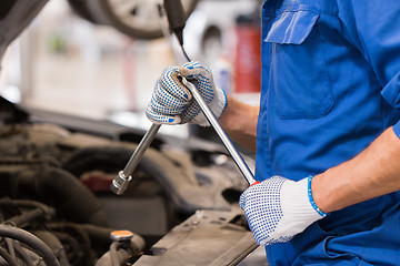 Image showing mechanic man with wrench repairing car at workshop