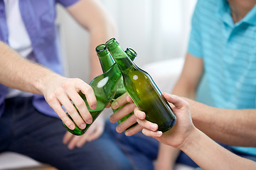Image showing close up of friends clinking beer bottles at home