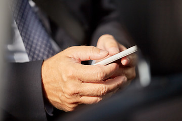 Image showing senior businessman texting on smartphone in car